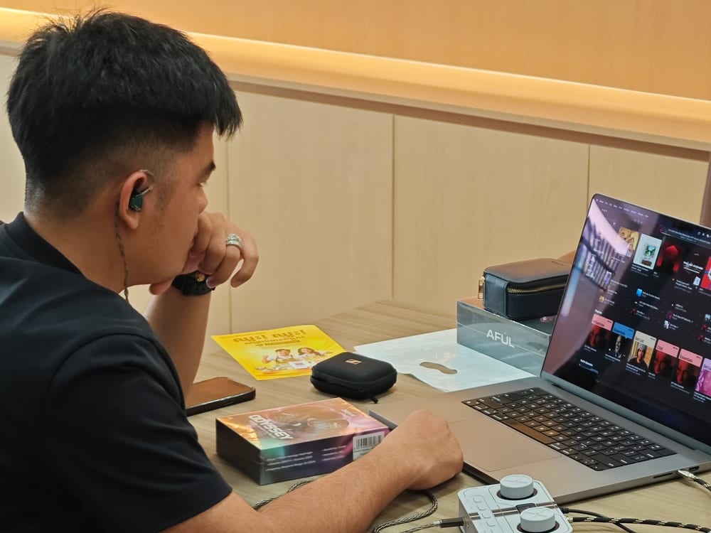 Auditioning a set of in-ear monitors at the shop desk, running from a laptop through a desktop headphone amplifier.