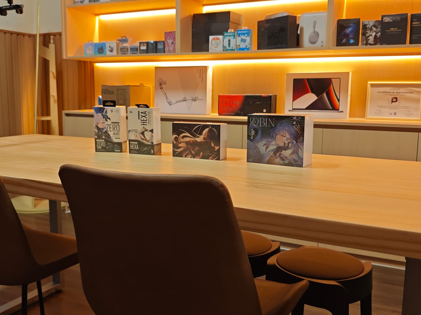 Boxed stock on the listening table: Truthear x Crinacle Zero Blue 2, Truthear Hexa, Moondrop Aria 2 and Moondrop Robin, with the lit shelves behind.