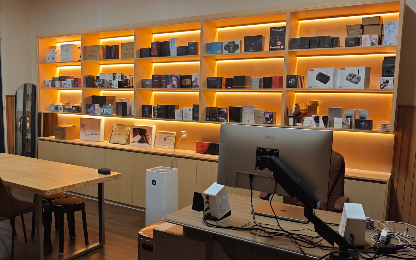 The display wall at Performance Store in Phnom Penh: five lit bays of in-ear monitor, headphone and DAC boxes, with the shop desk in front.